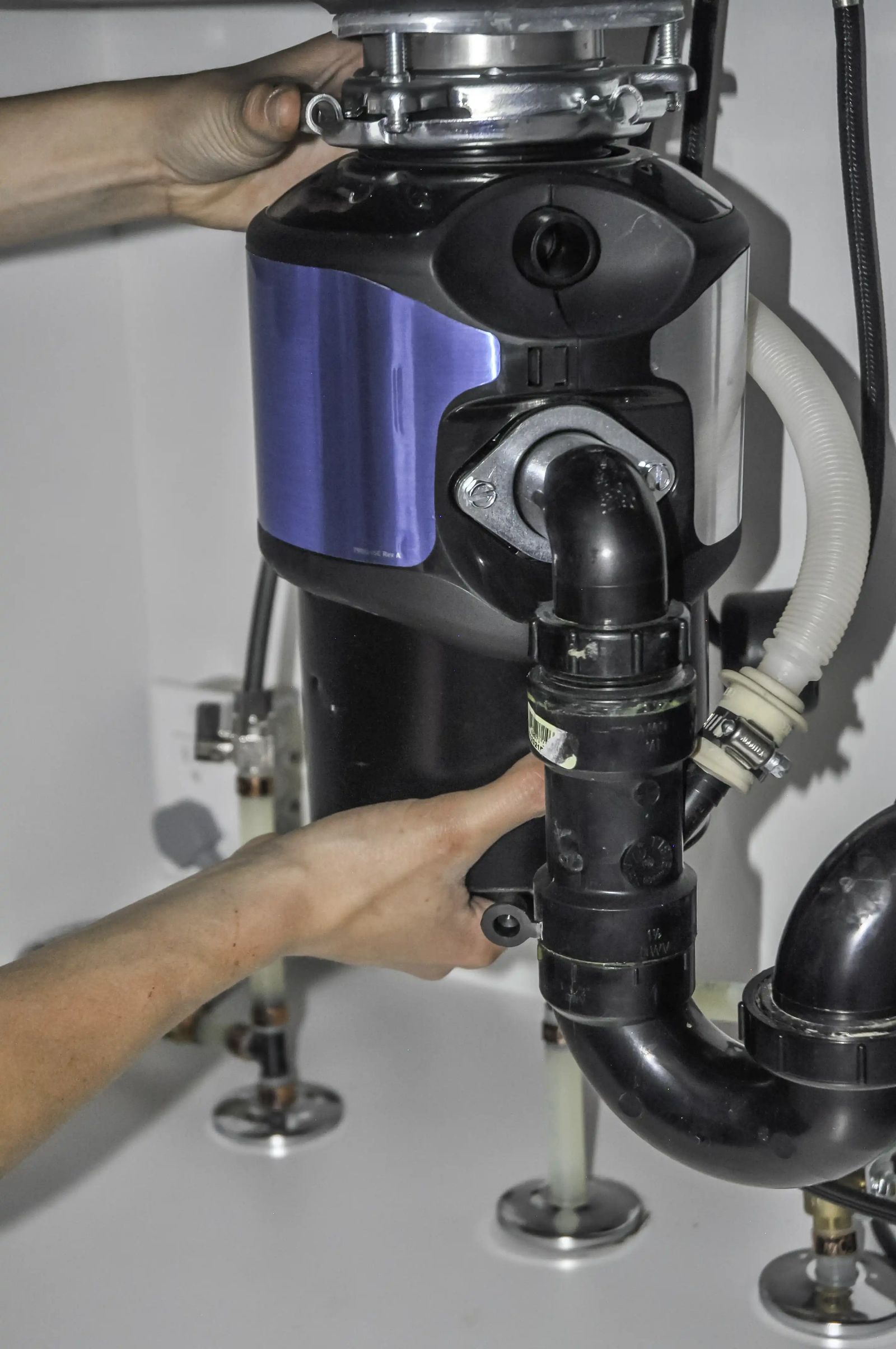 Technician installing a garbage disposal unit under a kitchen sink
